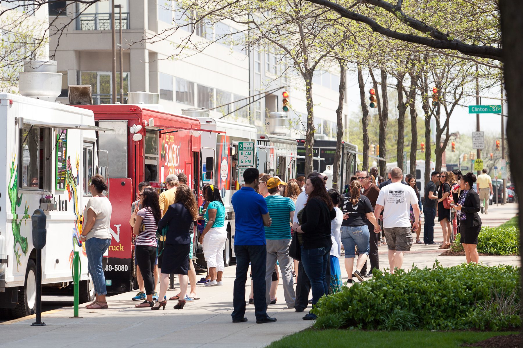 A crowd gathered around food trucks on a downtown street