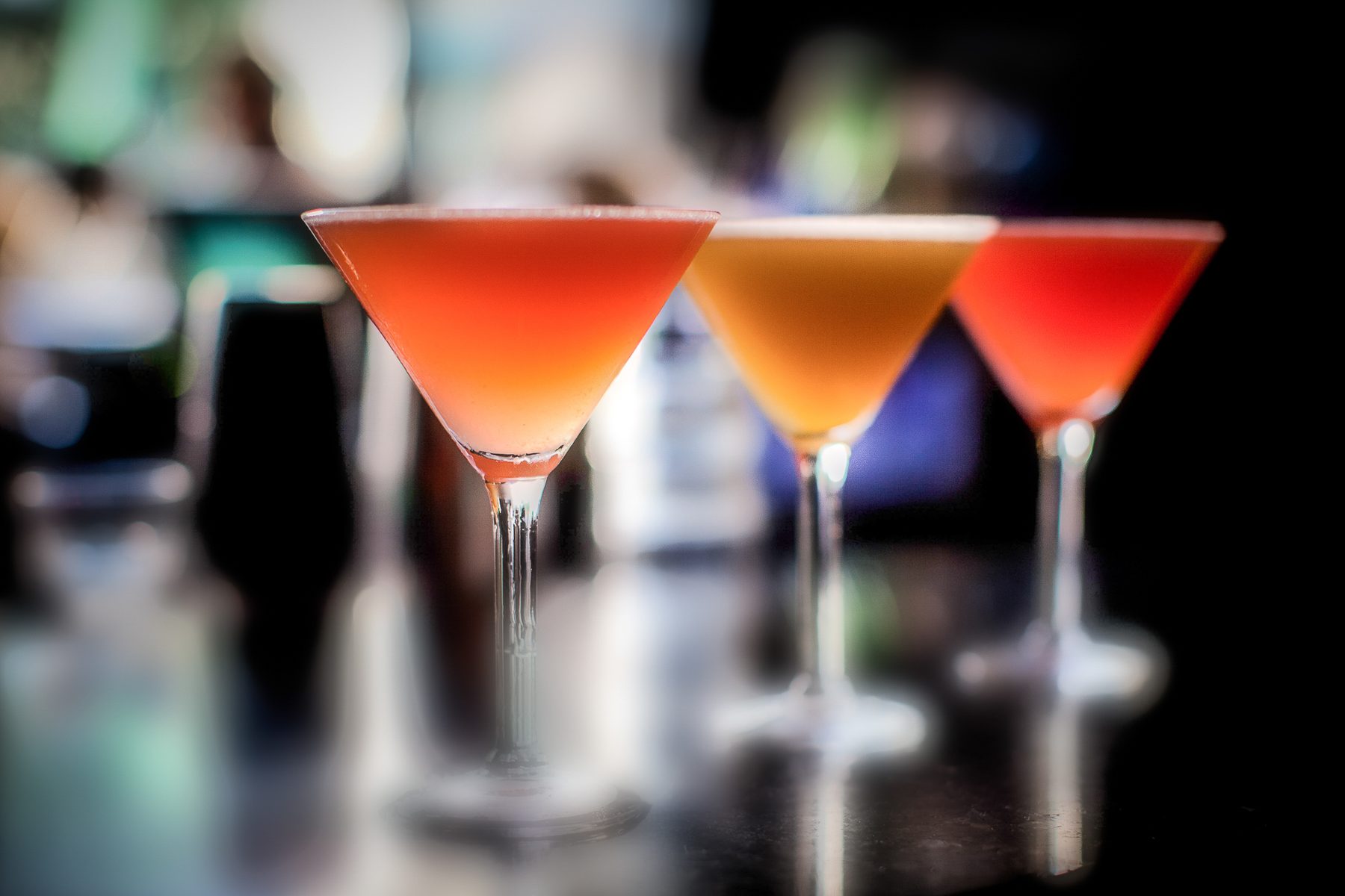 Three cosmopolitans lit against a dark bar